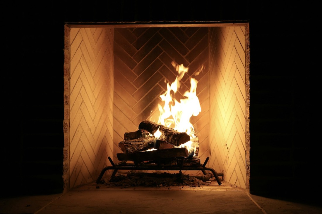 Feu de bûches dans un foyer en briques à chevrons, ambiance nocturne